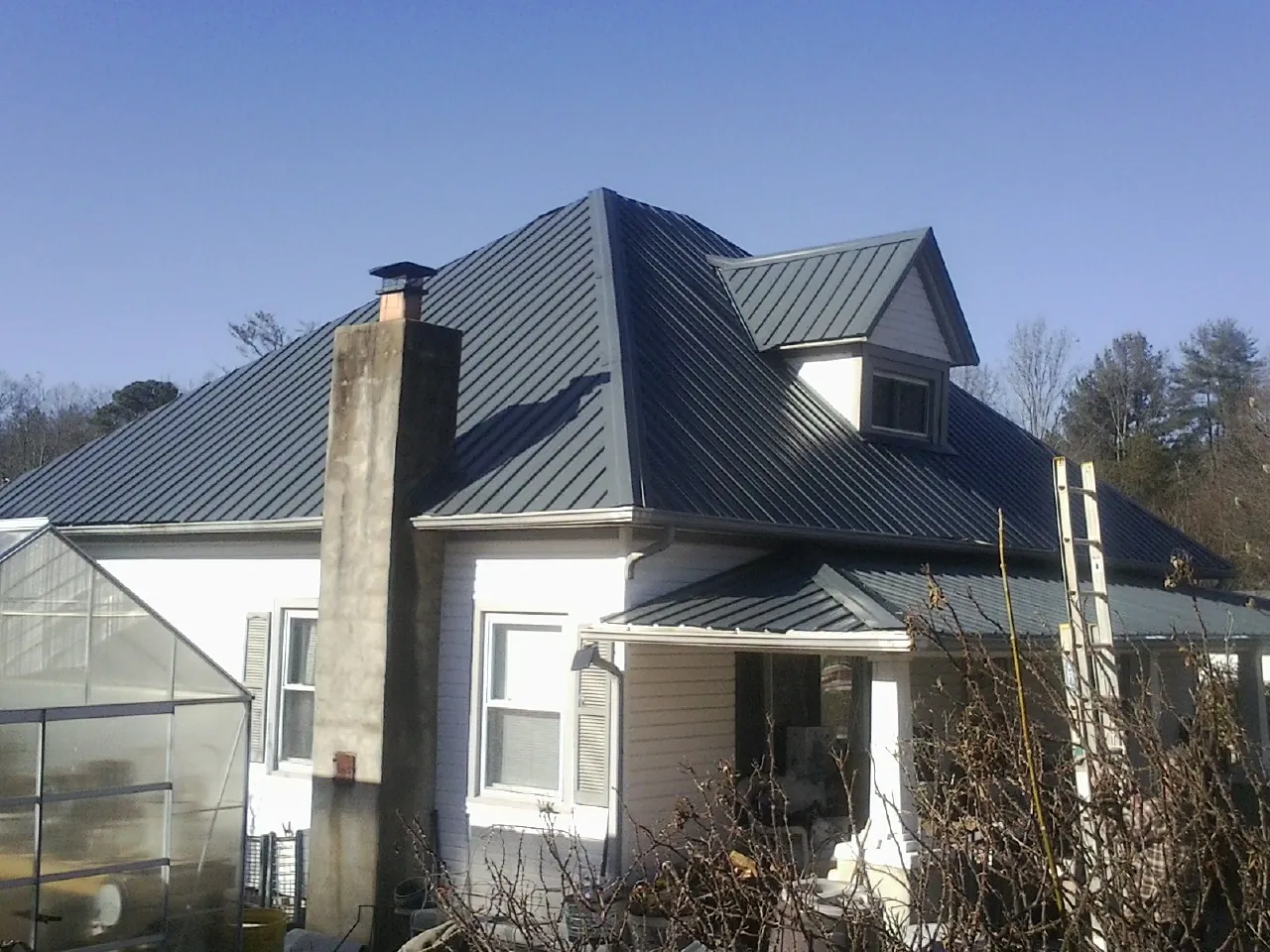 Dark blue standing seam metal roof on a white farmhouse with dormer — Slate & Tile Roof Repair by Roofing Brothers in Ardsley