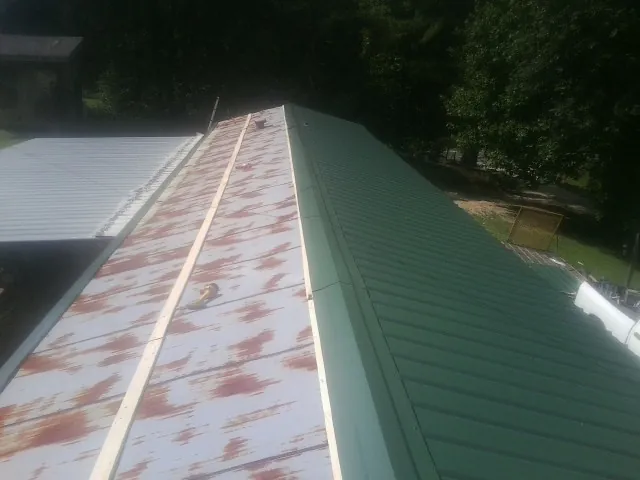 Old rusted panels beside newly installed green metal roofing — Wind Damage Roof Repair by Roofing Brothers in Ardsley