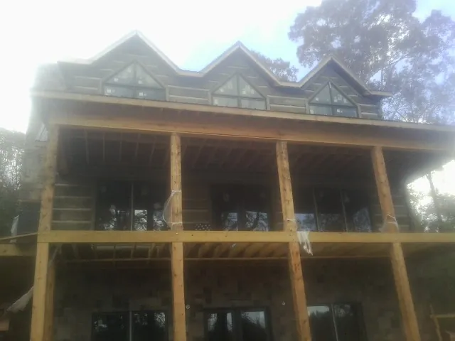 Dormers and porch framing on a large log home under construction — Roof Coating work by our crew in Ardsley