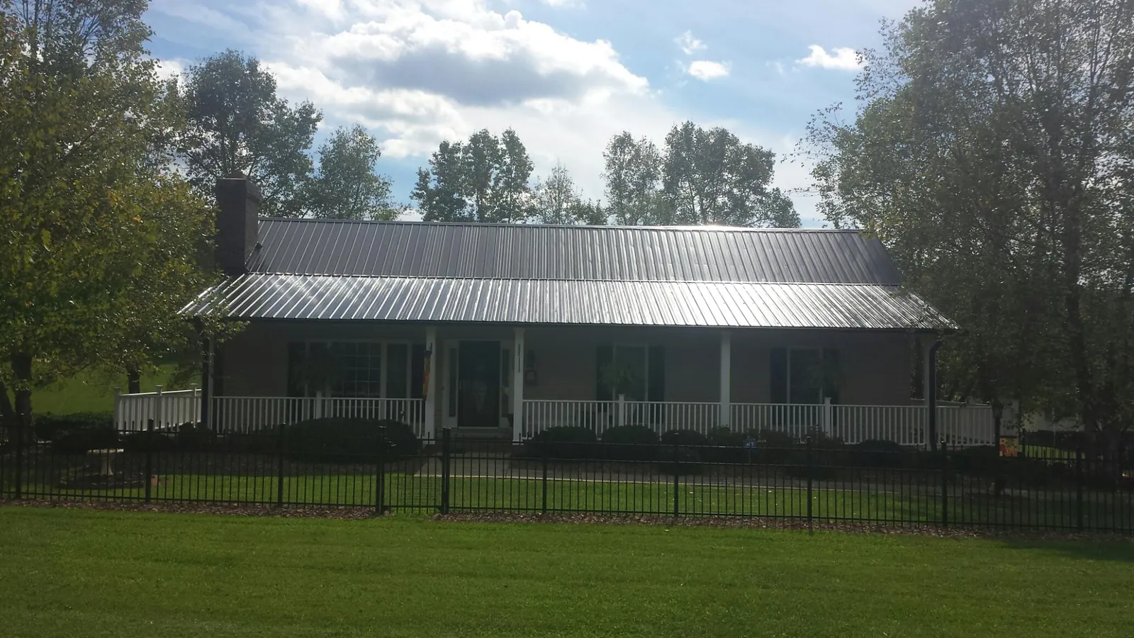 Gray metal roof on a brick ranch with a full width front porch — Gutter Guard Installation work by our crew in Ardsley