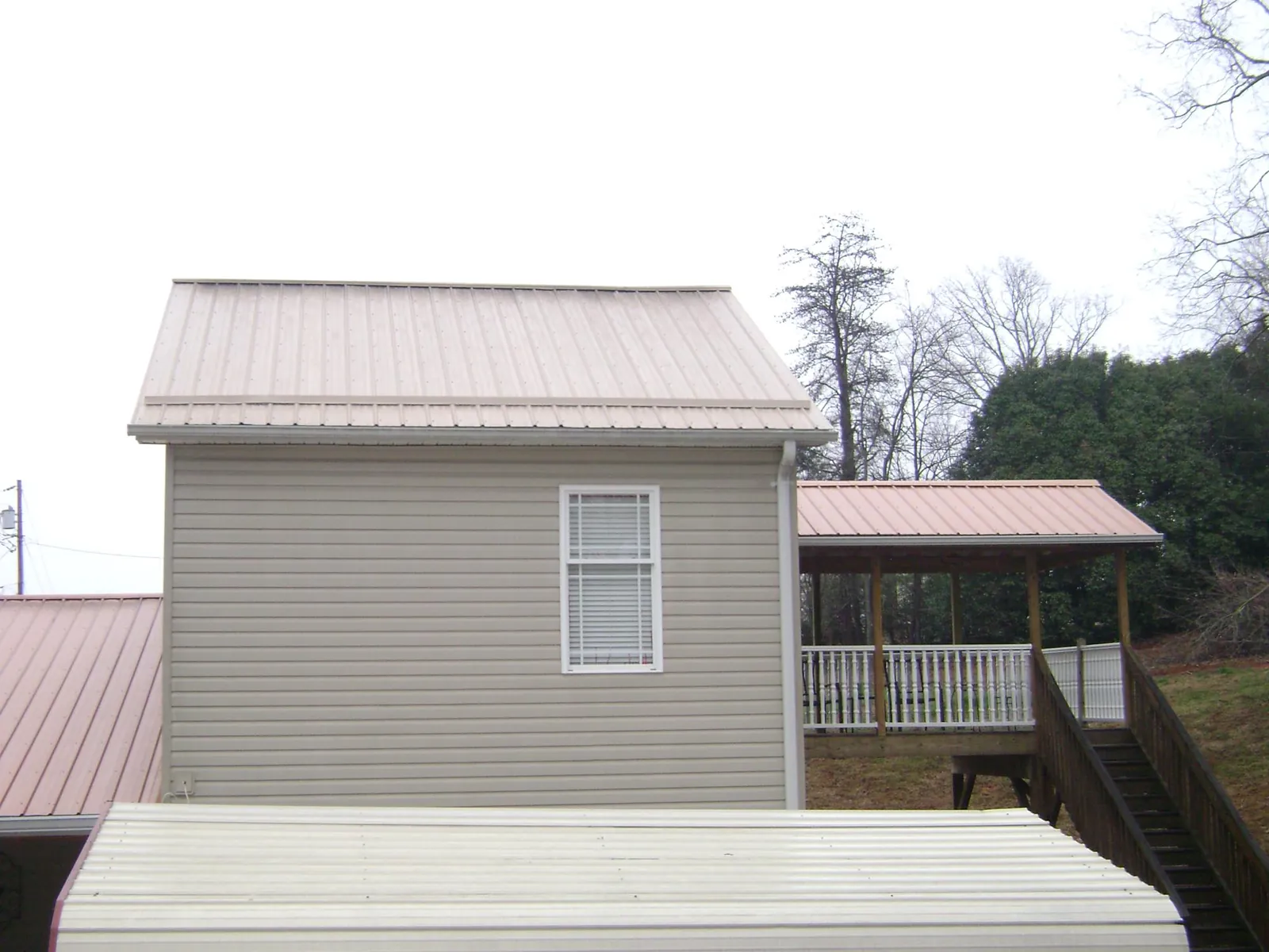 Tan metal roofs on a two story addition and attached porch, from a Roof Replacement job in Ardsley